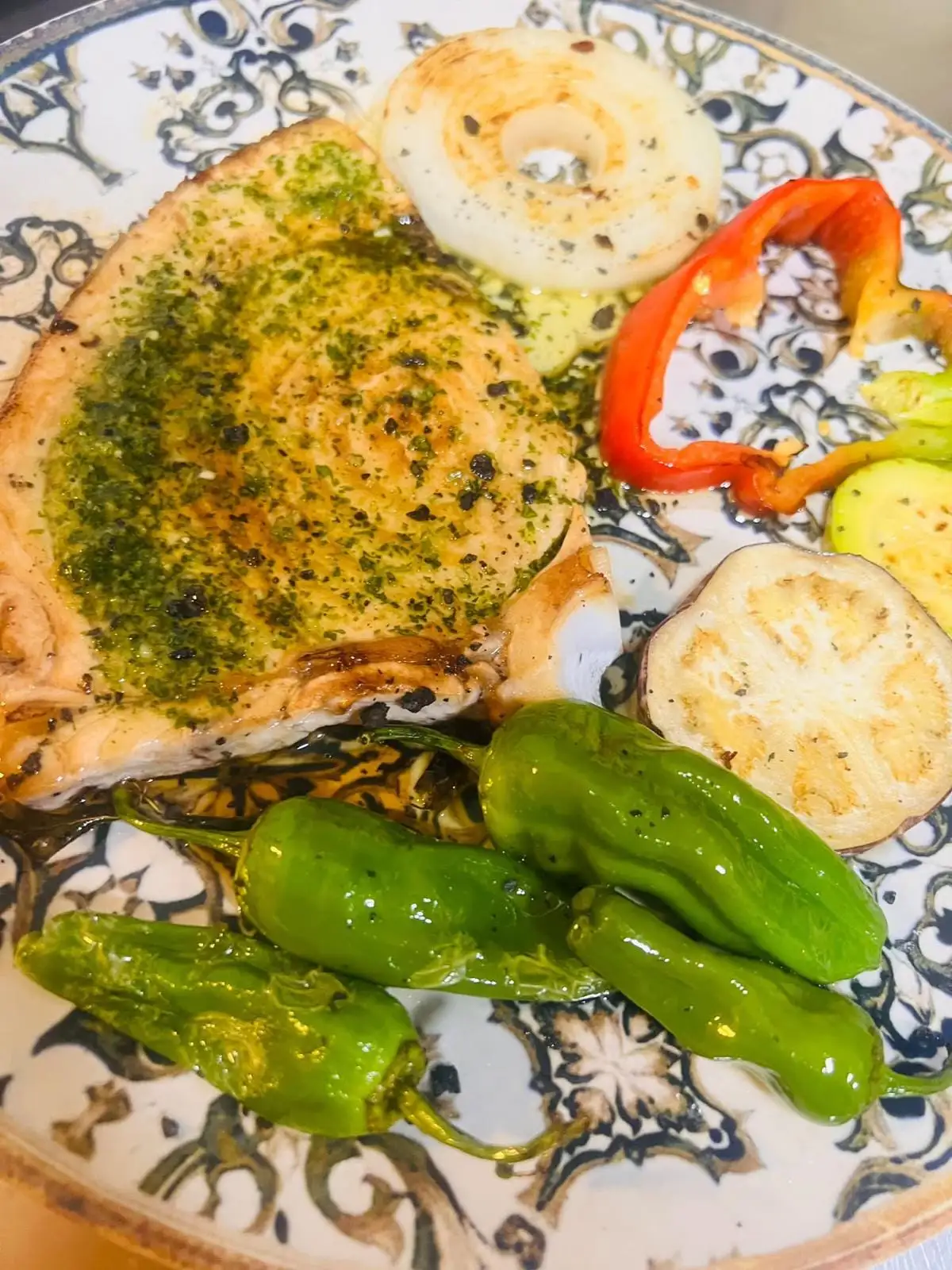 A grilled fish steak with green garlic and parsley sauce, with grilled onion, red pepper, courgette and aubergine, and Padrón peppers.