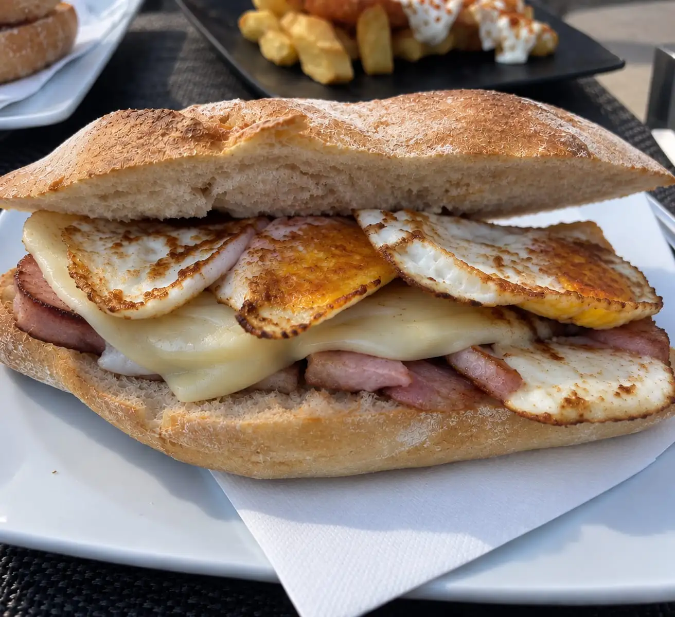 Crusty roll with pork loin, melted cheese and two fried eggs, served on the terrace.