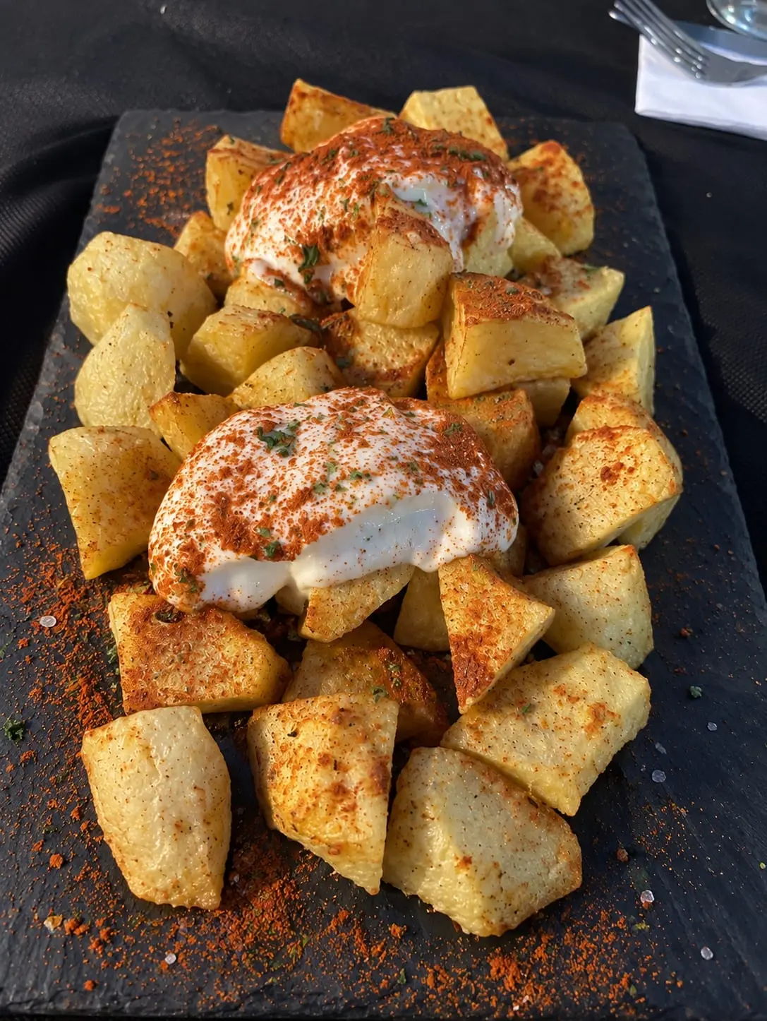 Creïlles braves servides en una pissarra, amb dos muntons de salsa blanca espolsada de pebre roig.
