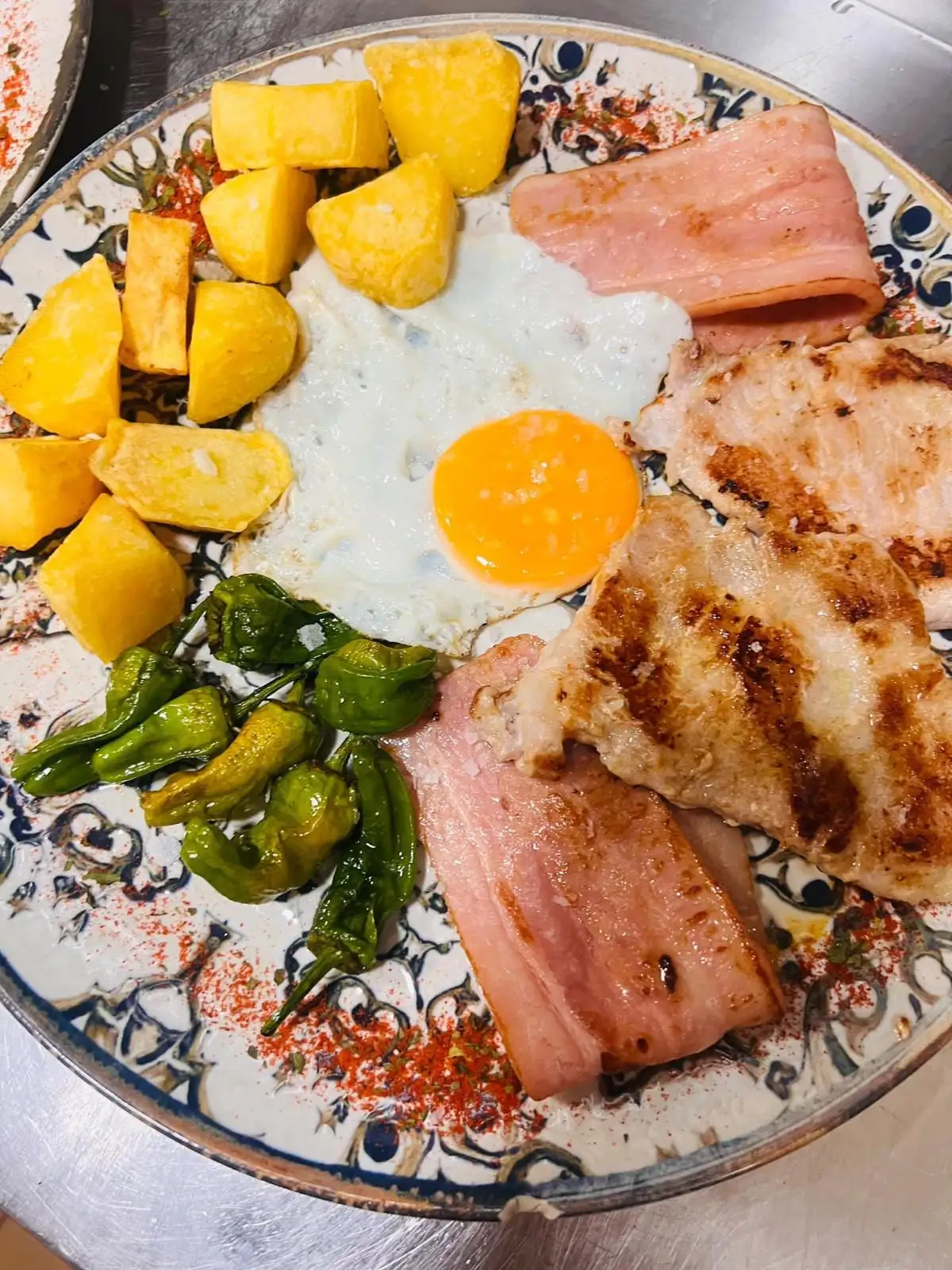 A mixed plate: grilled pork loin and ham, a fried egg, potatoes and Padrón peppers.
