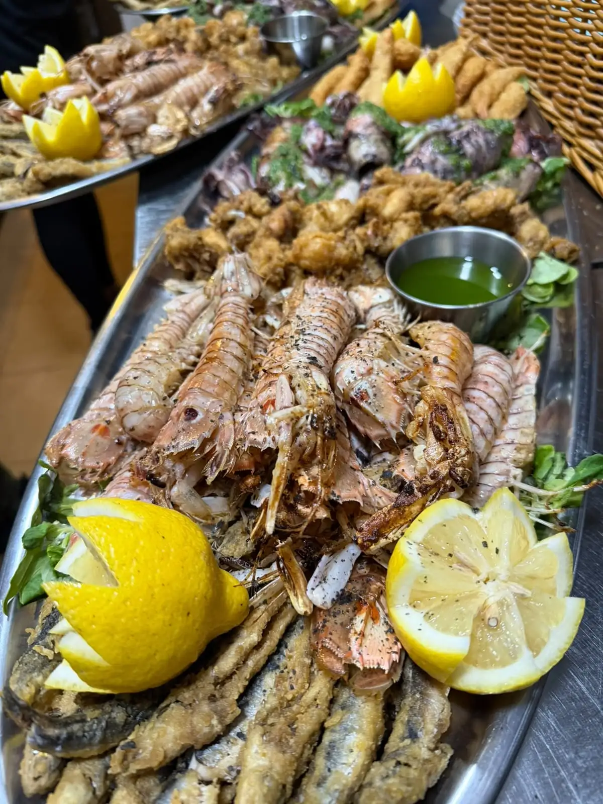 A seafood platter: grilled mantis shrimp and prawns, fried anchovies and a small bowl of green sauce.